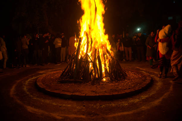 Gurgaon, India, Circa 2020 - Photograph of a giant bonfire lit for the auspicious festival of lohri or Holi or Holika Dahan. The fire is surrounded by people enjoying the festival. This is a spring harvest festival celebrated in India by roasting grain, popcorn, sesame seeds, chikki, peanuts and collecting coal